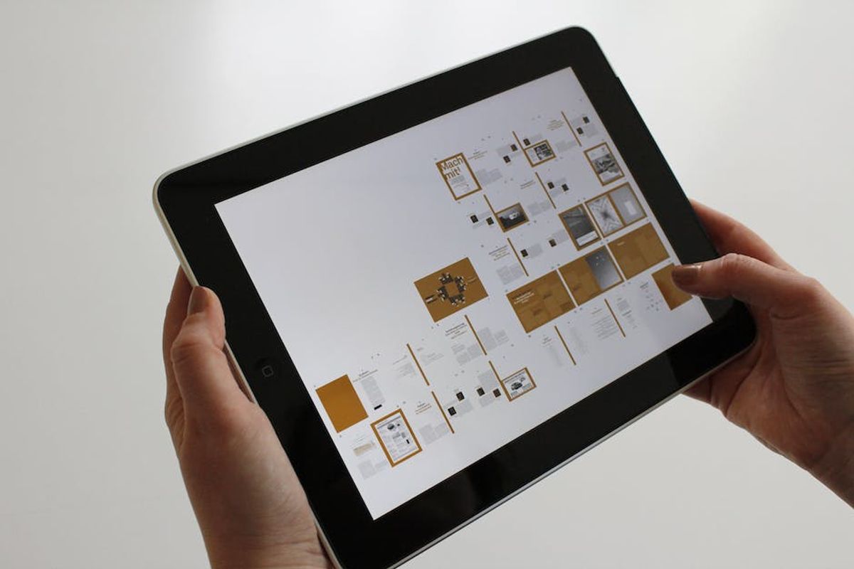 Hands holding a tablet displaying a media plan layout of ad placements and pages