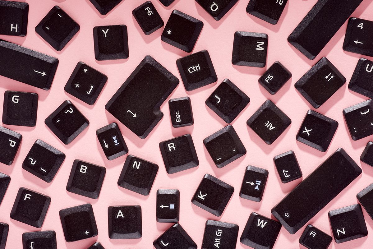 Scattered black keyboard keys arranged on a pink surface, shot from overhead