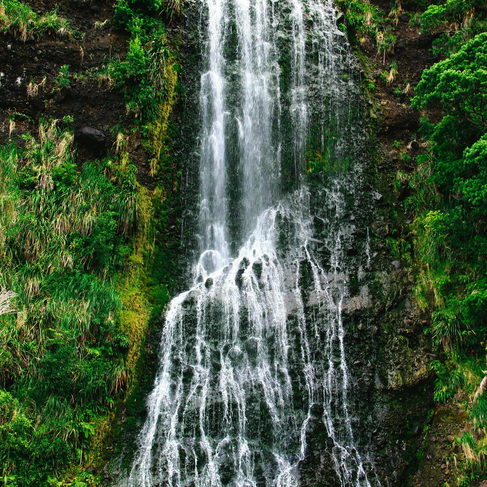Wasserfall stürzt über grüne Felsen in die Tiefe