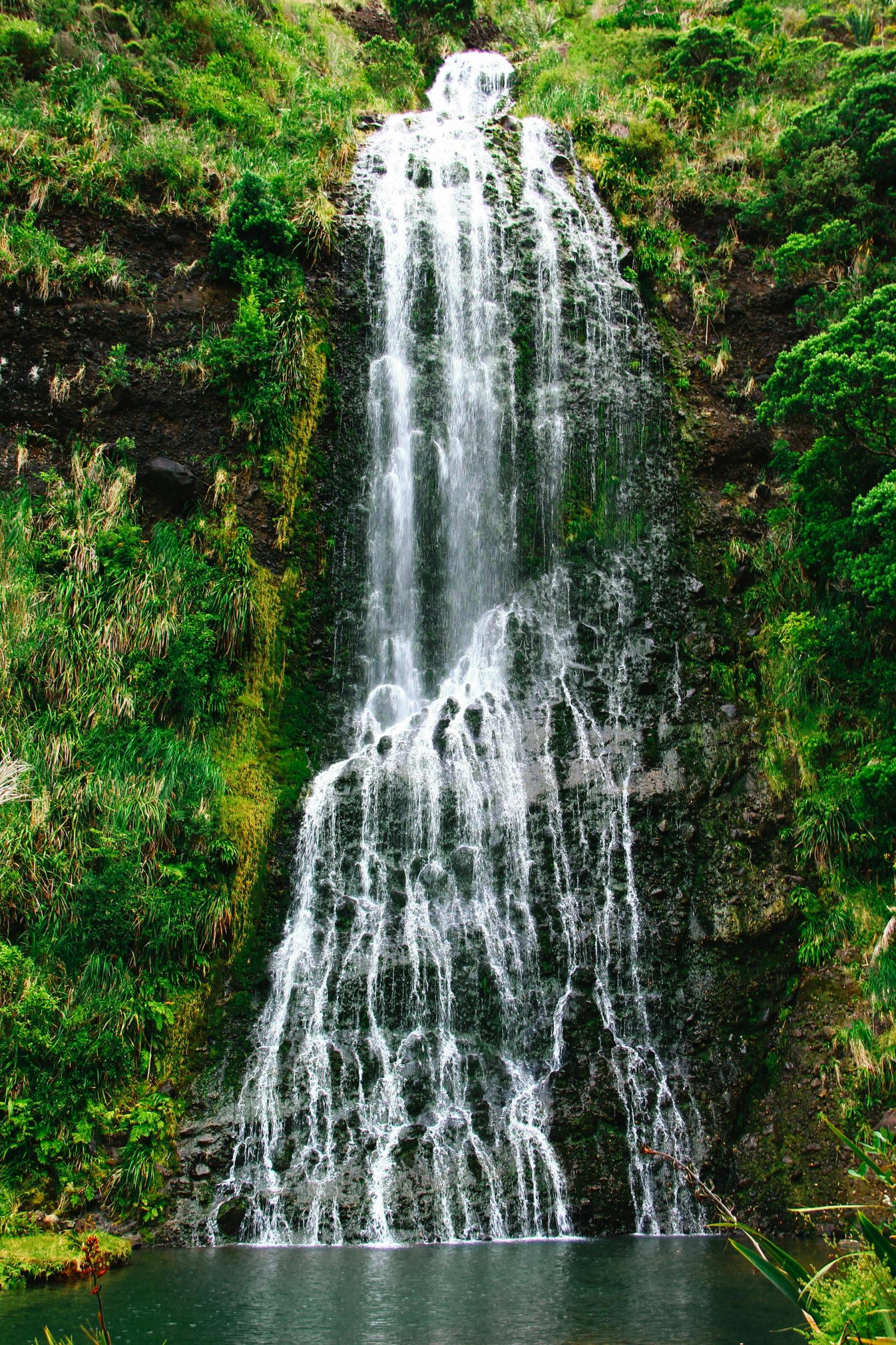 Wasserfall stürzt über grüne Felsen in die Tiefe