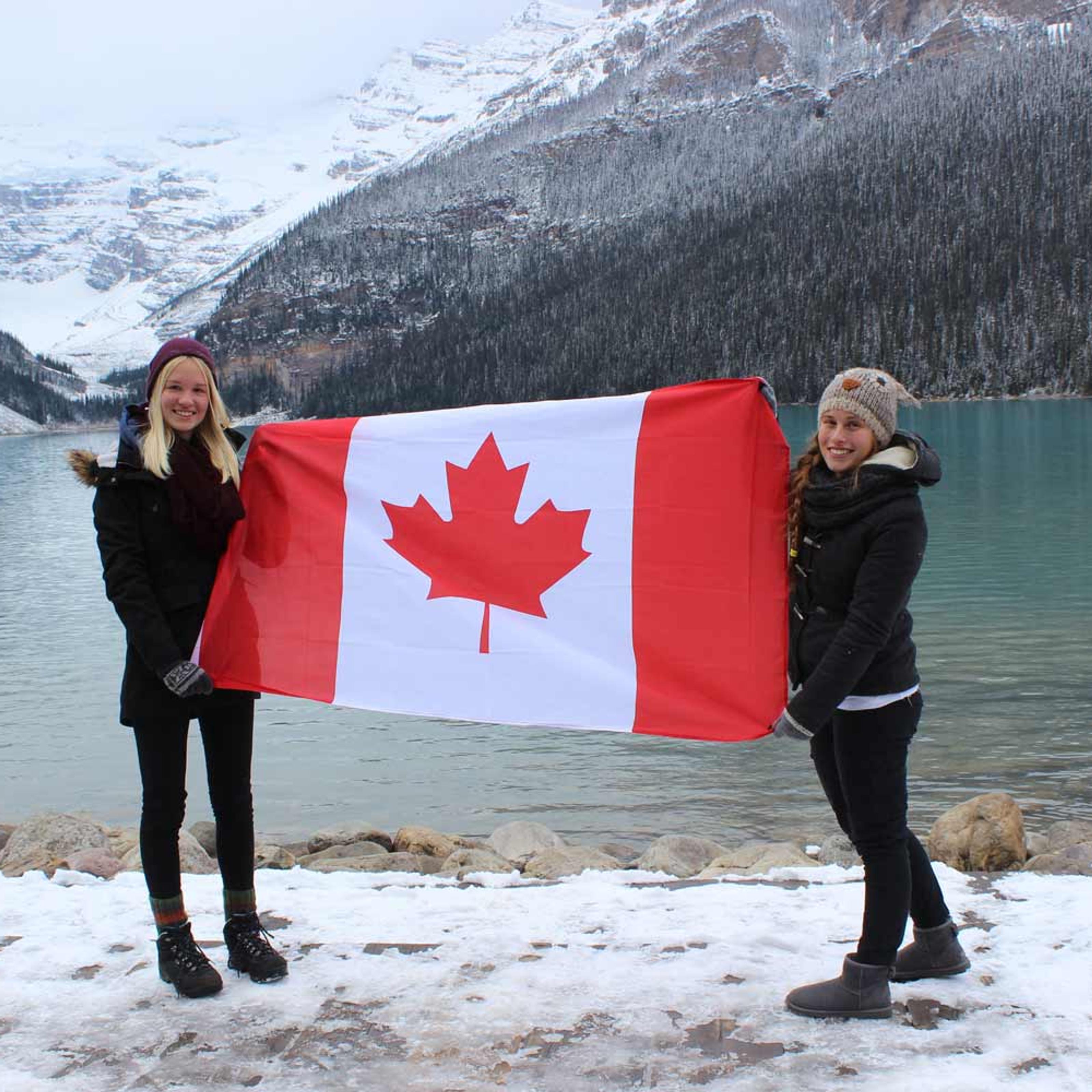 Zwei junge Frauen halten die kanadischen Flagge, an einem Seeufer