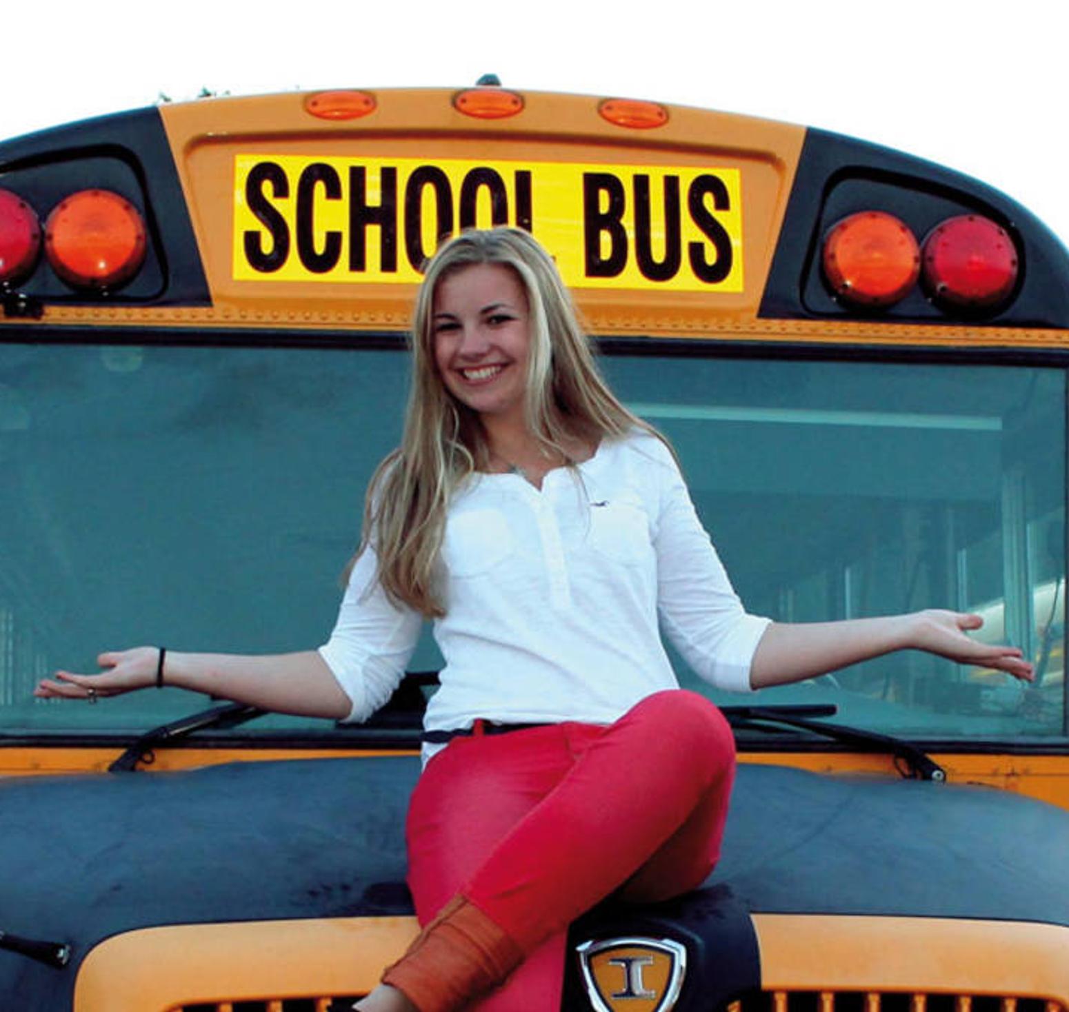 Frau sitzt auf einem Schulbus und lächelt