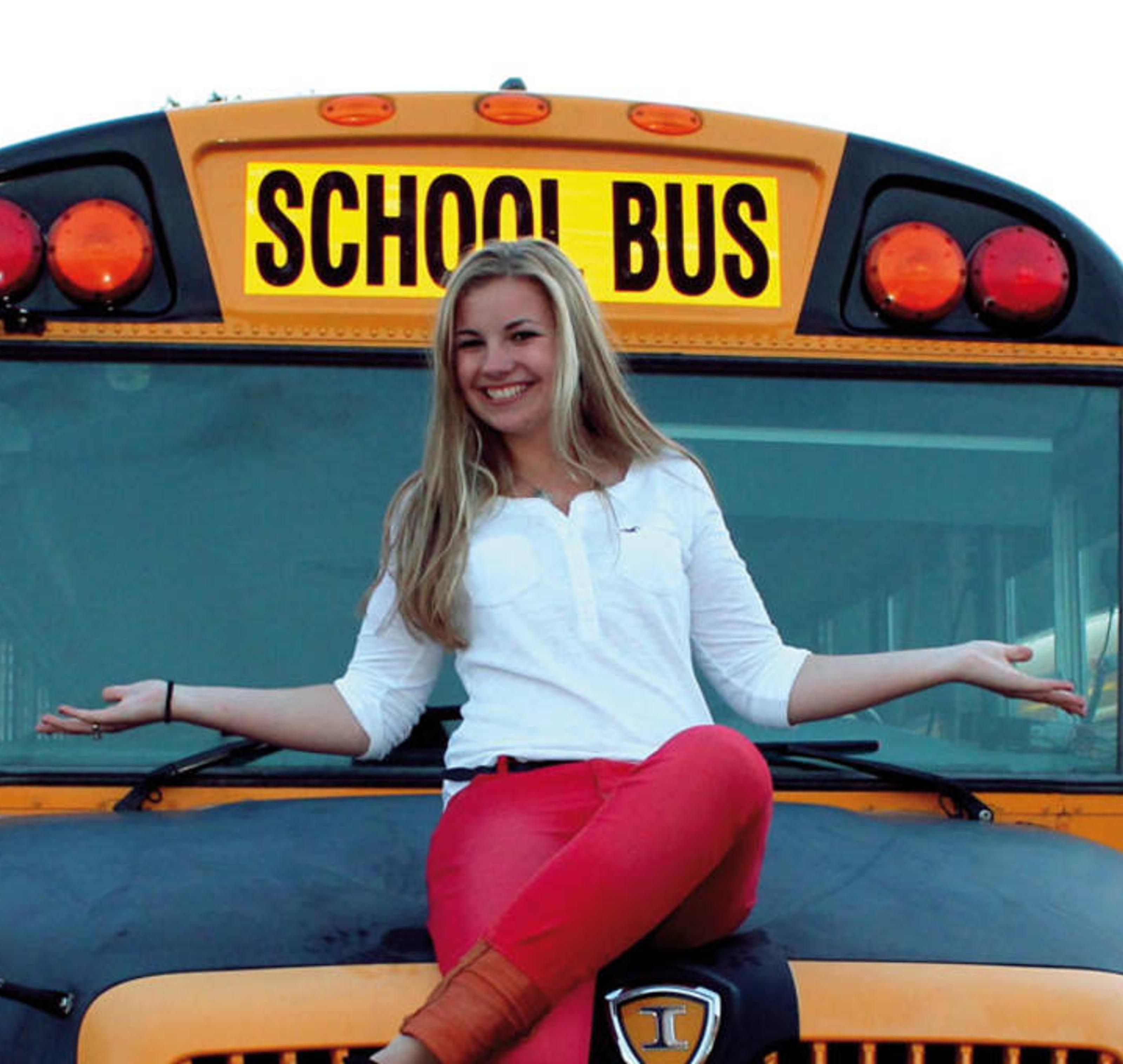 Frau sitzt auf einem Schulbus und lächelt