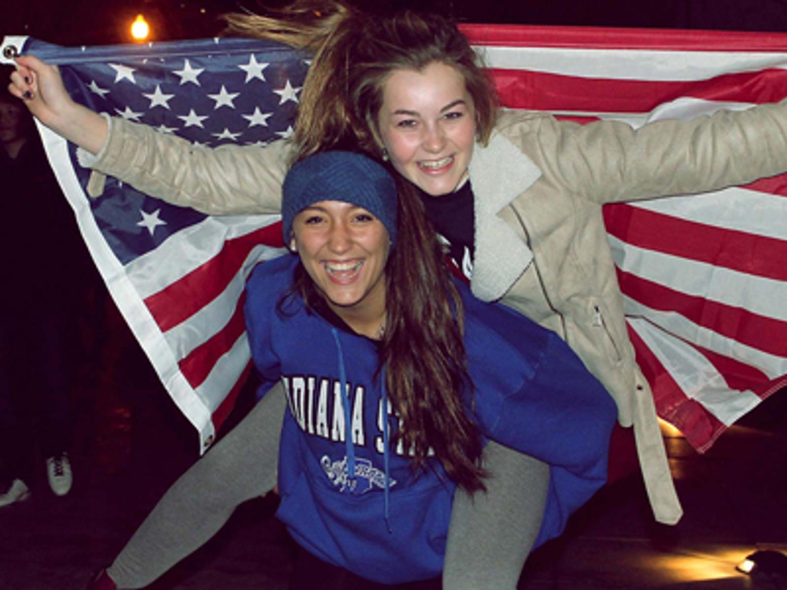 Zwei fröhliche Austauschschülerinnen mit US-Flagge beim Schüleraustausch in den USA – Freundschaft, Abenteuer und unvergessliche Erlebnisse mit dem USA Classic Programm.