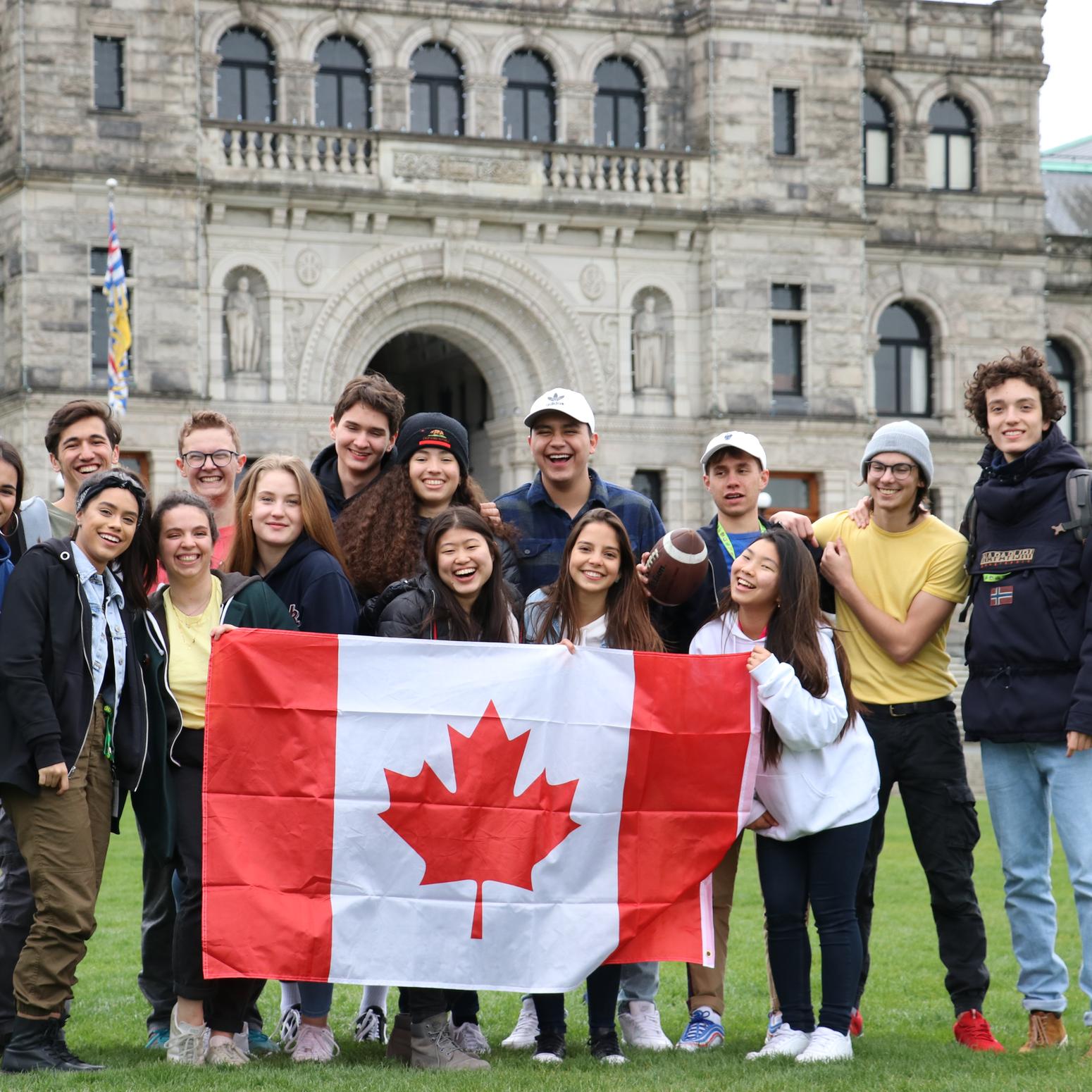 Schülergruppe mit kanadischer Flagge vor altem Gebäude