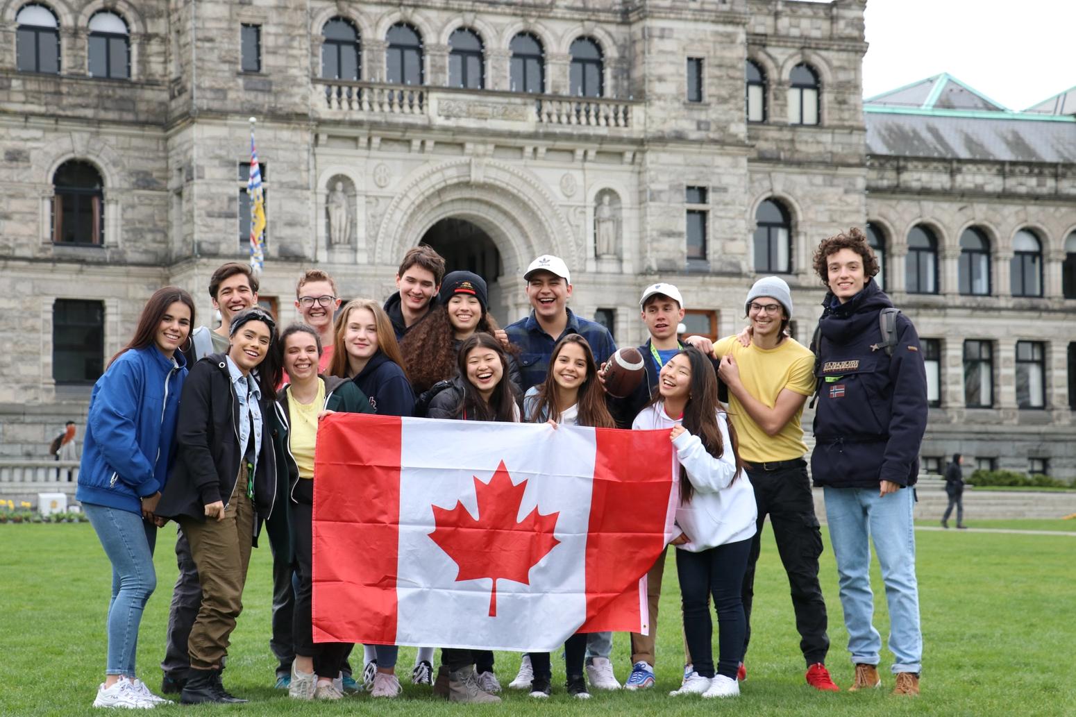 Eine Gruppe Schüler hält eine Kanada-Flagge und lächelt in die Kamera