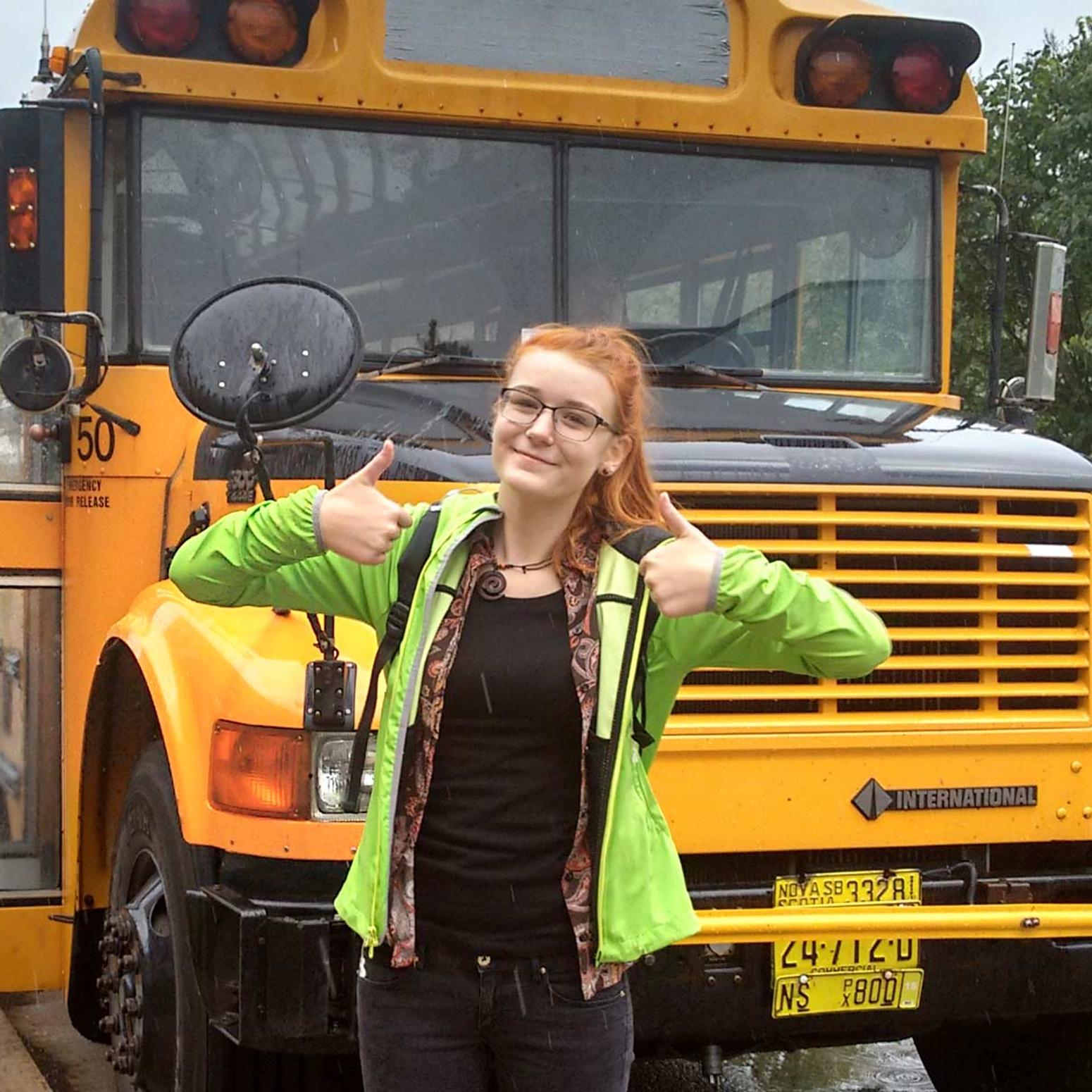 Junge Frau posiert vor einem Schulbus