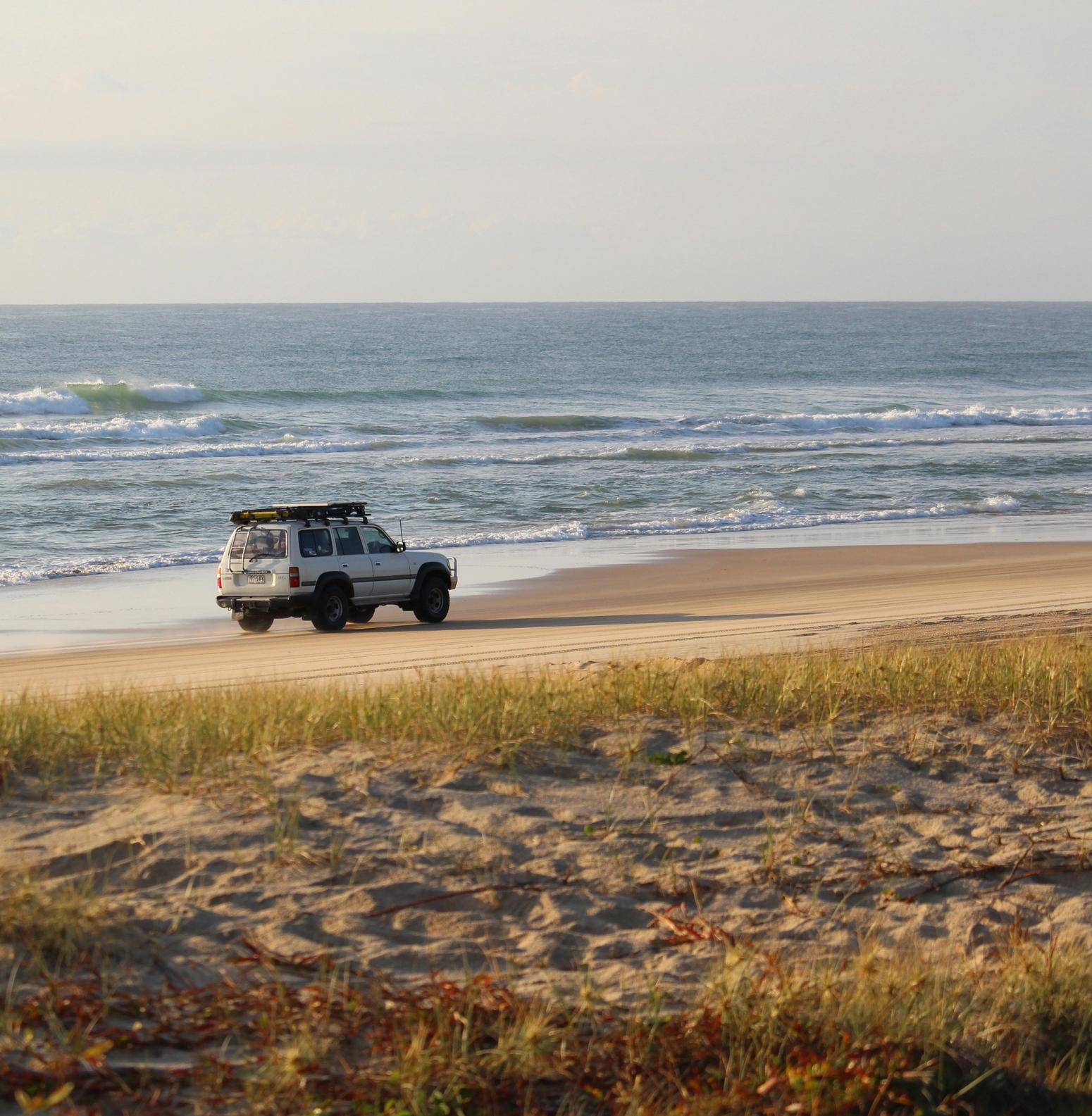 Ein Auto an einem breiten Sandstrand