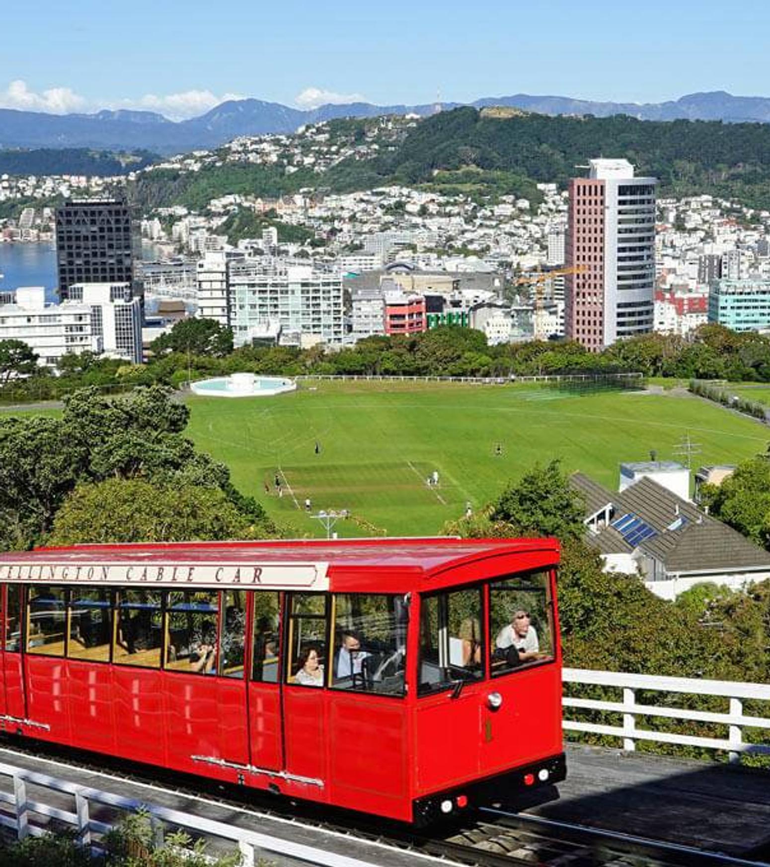 Eine rote Straßenbahn fährt einen Hügel in einer kleinen Stadt hinauf