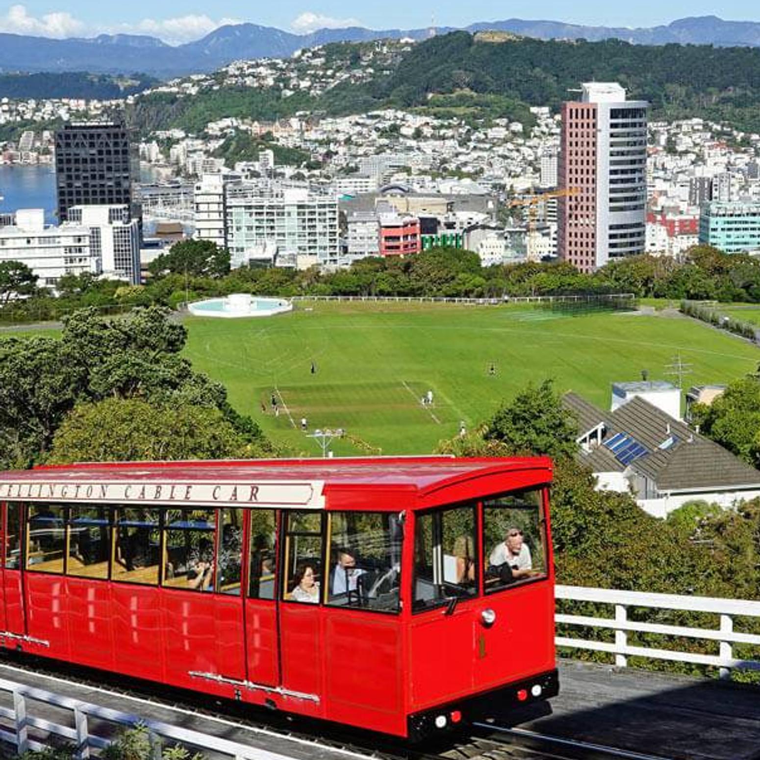 Eine rote Straßenbahn fährt einen Hügel in einer kleinen Stadt hinauf 