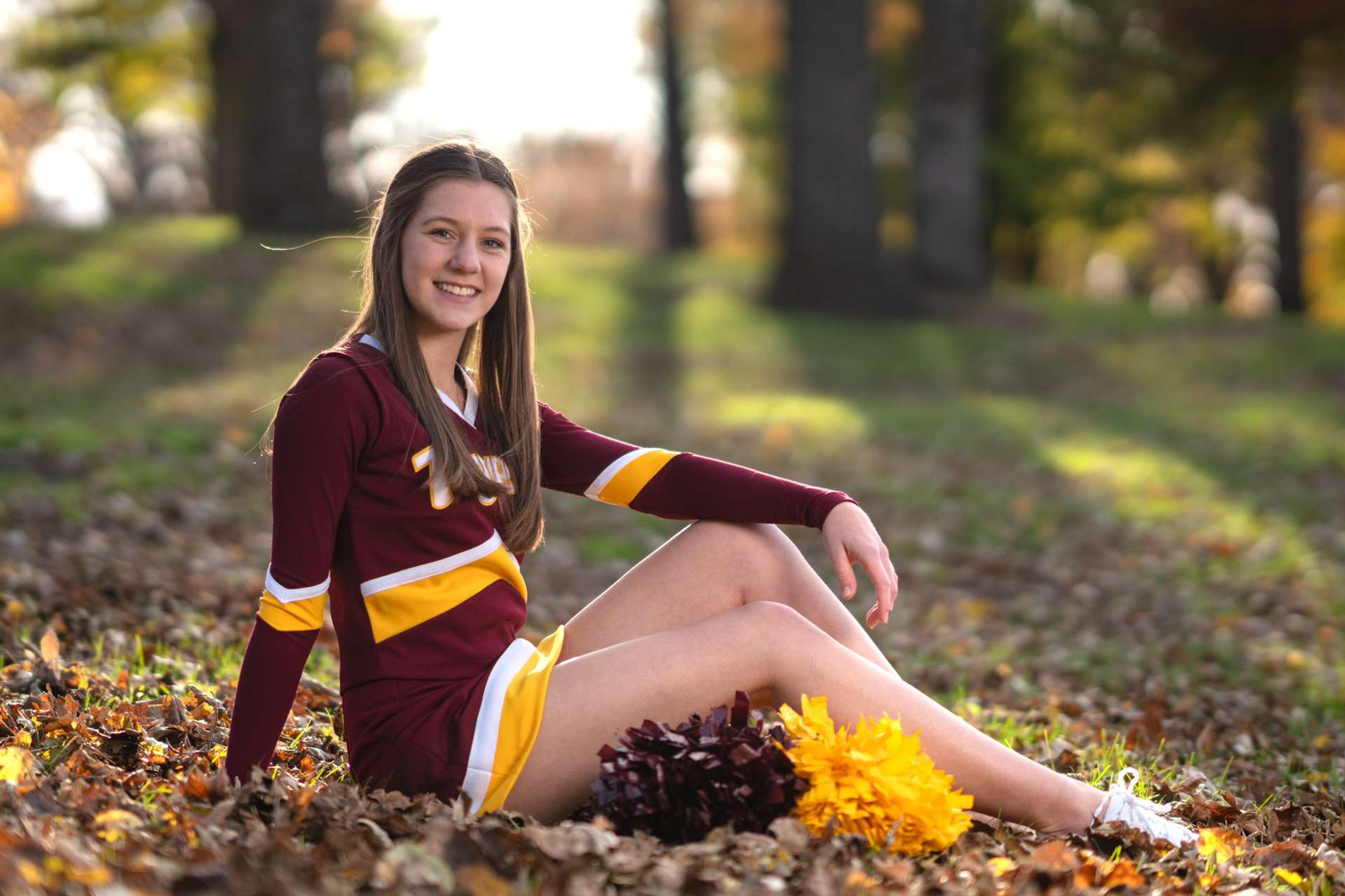 Cheerleaderin sitzt im Laub