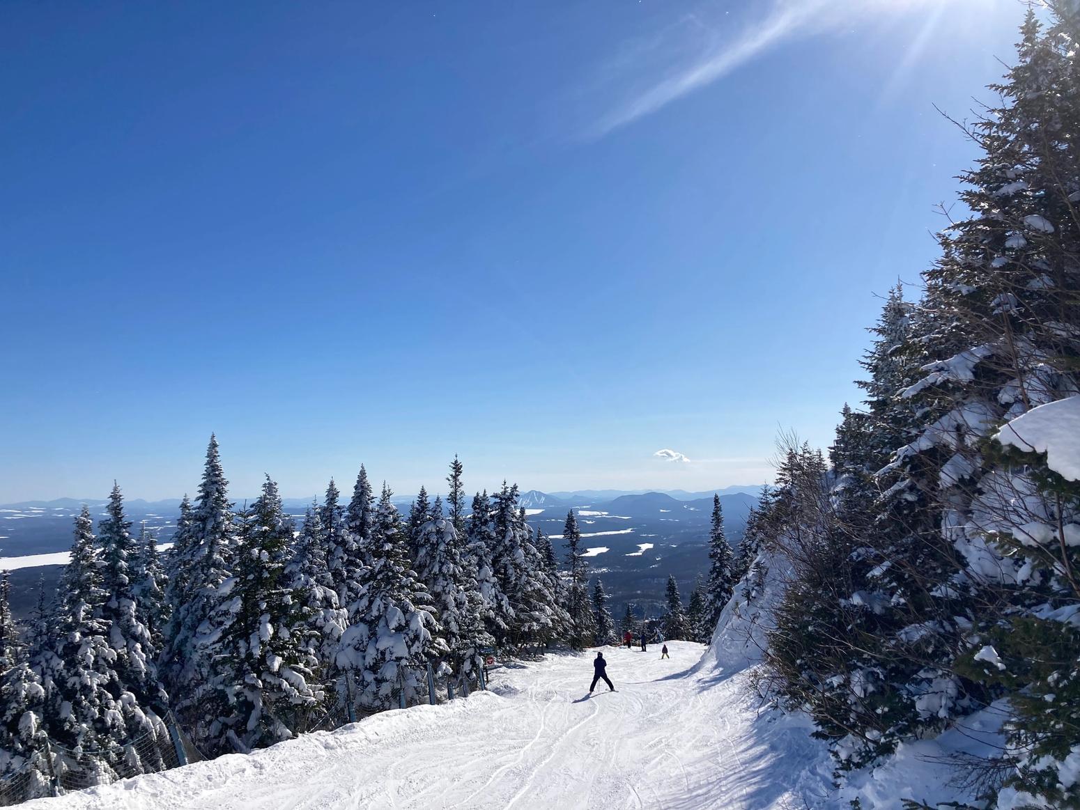 Skifahrer:innen in Quebec Kanada auf Schnee mit blauem Himmel
