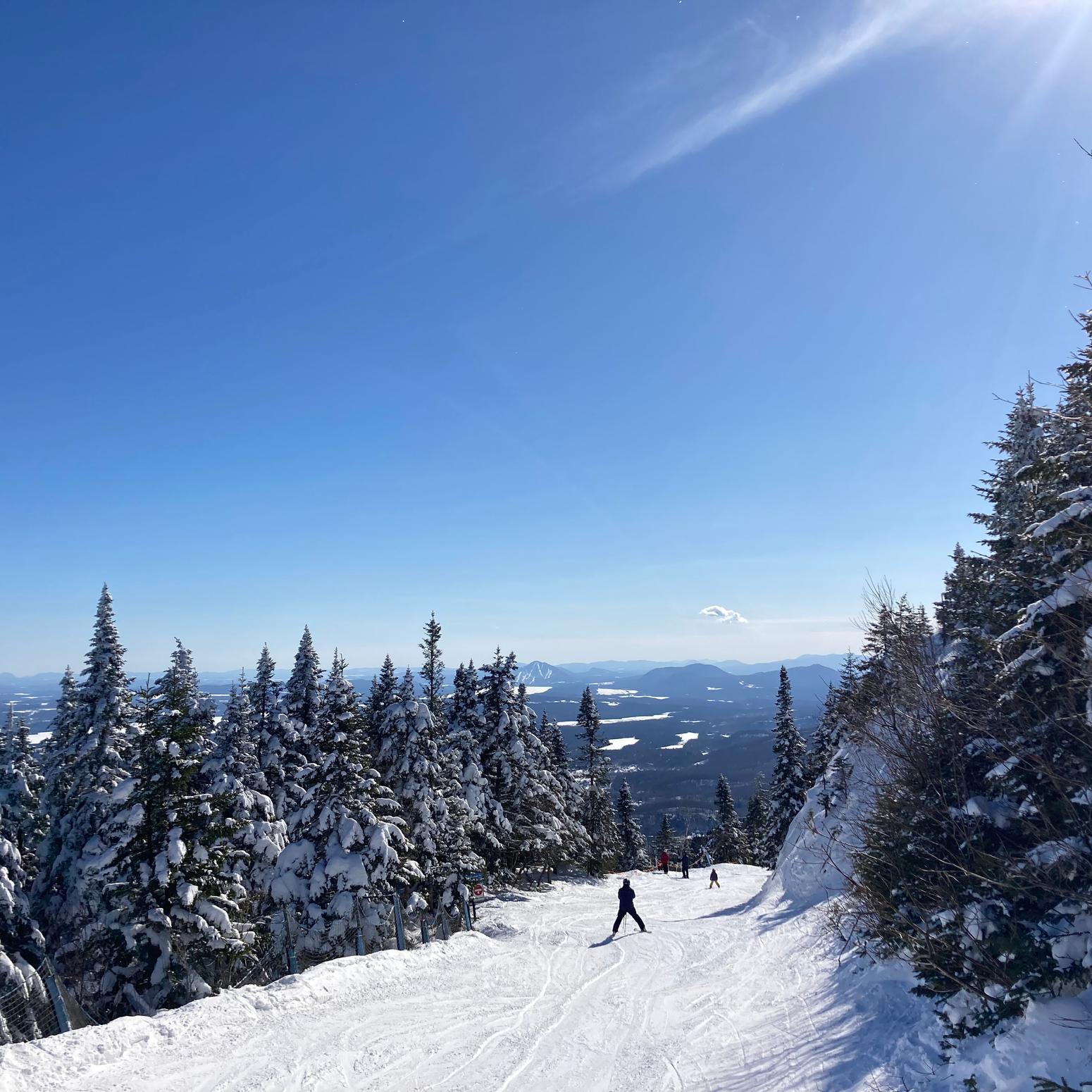 Skifahrer:innen in Quebec Kanada auf Schnee mit blauem Himmel