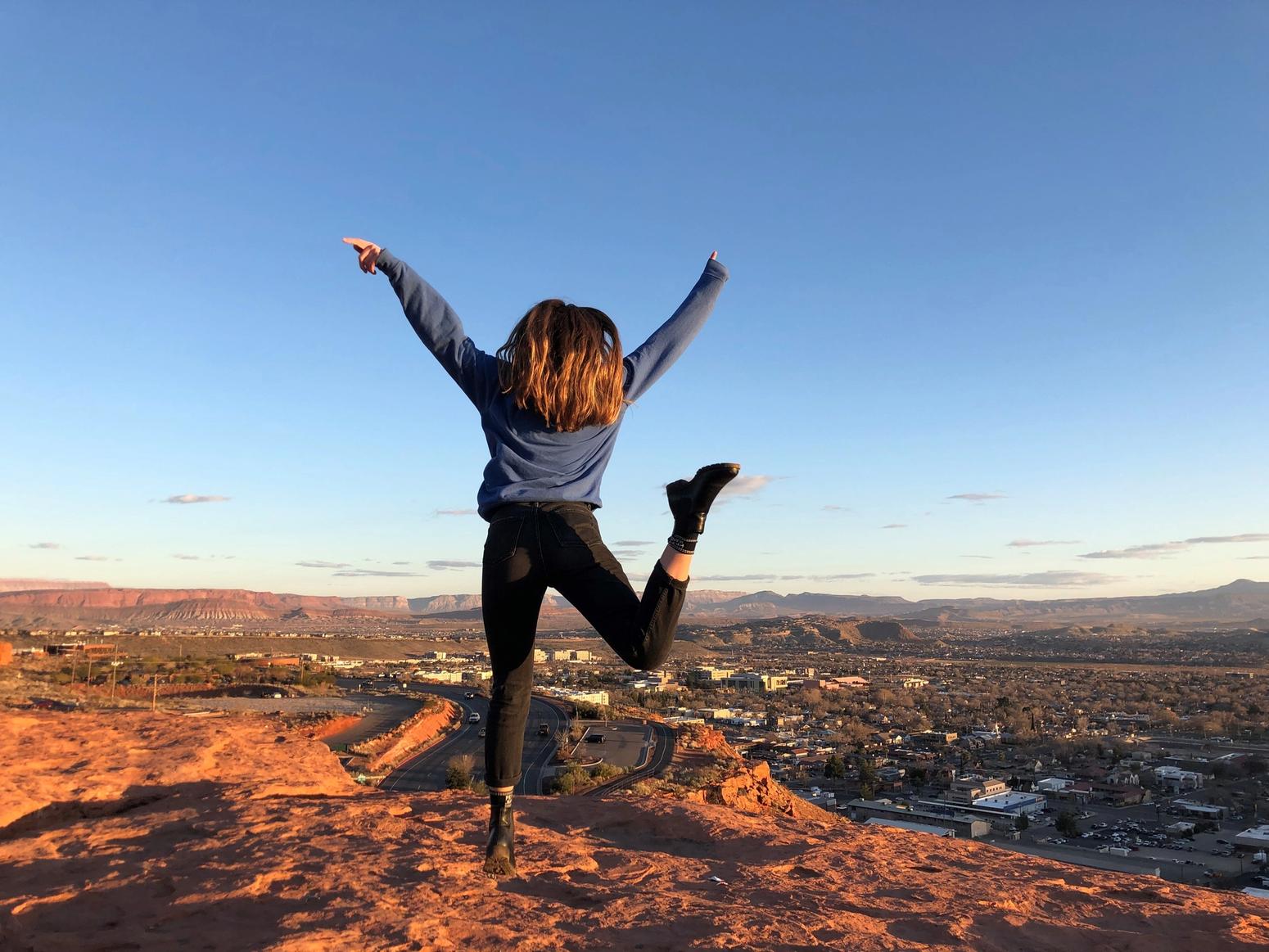 Junge Frau springt auf einem Berg in Arizona in die Luft