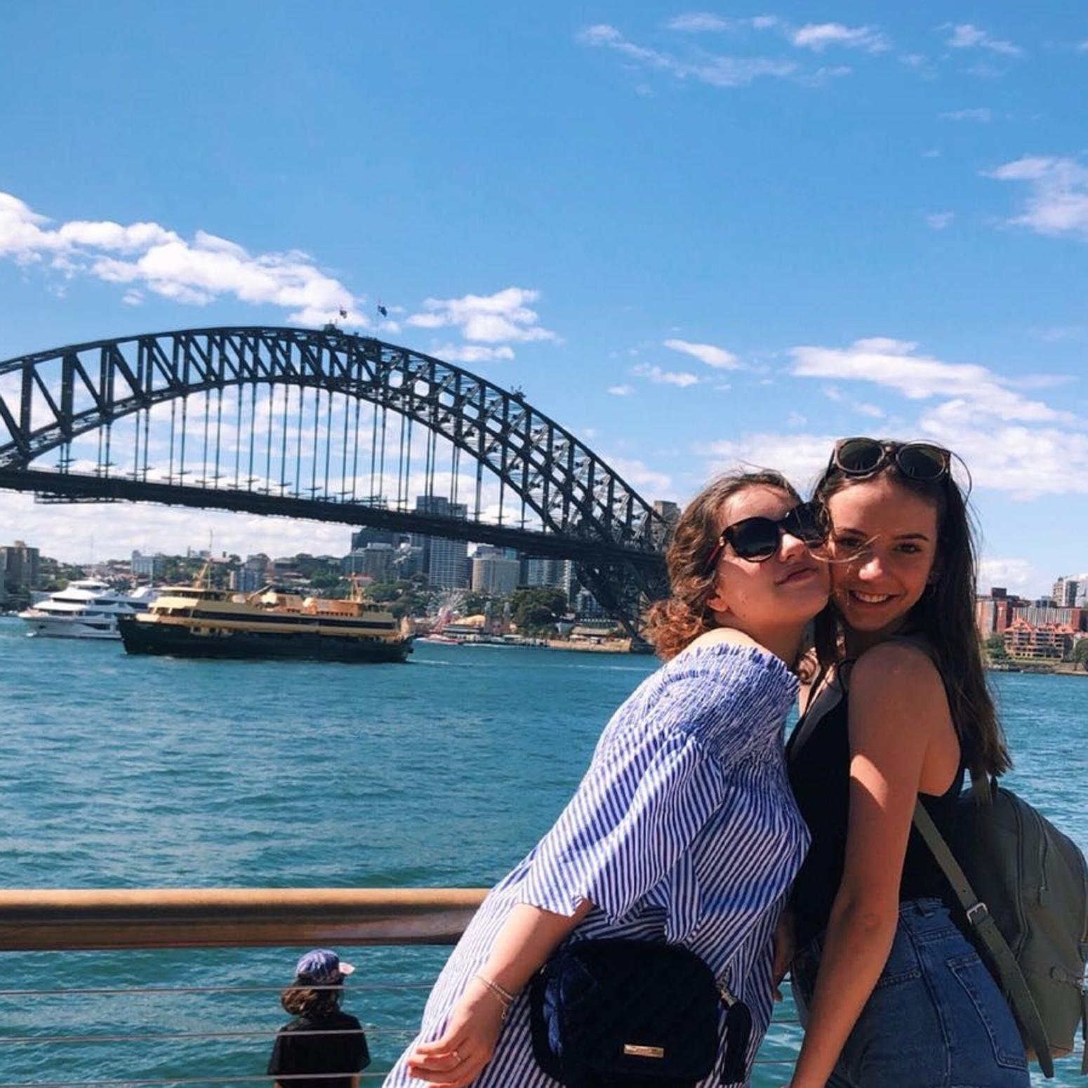 Zwei junge Frauen stehen vor der Sydney Harbour Bridge