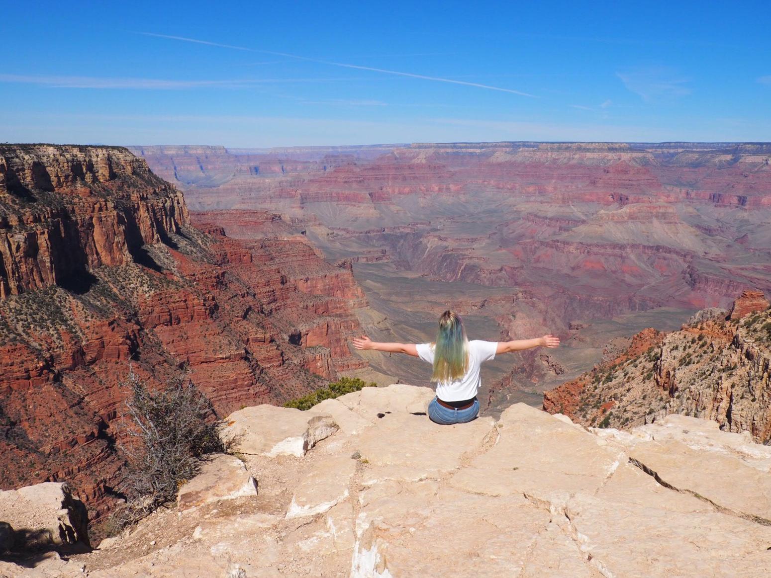 Mädchen sitzt am Rand eines Canyons