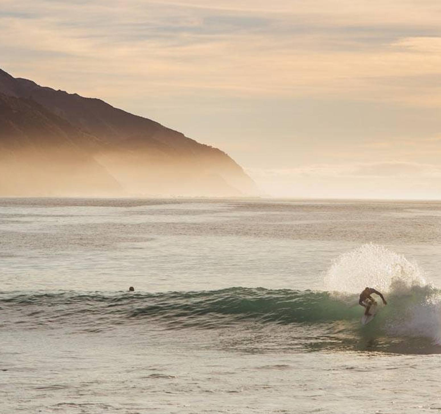 Ein Mann steht am Strand und beobachtet Surfer