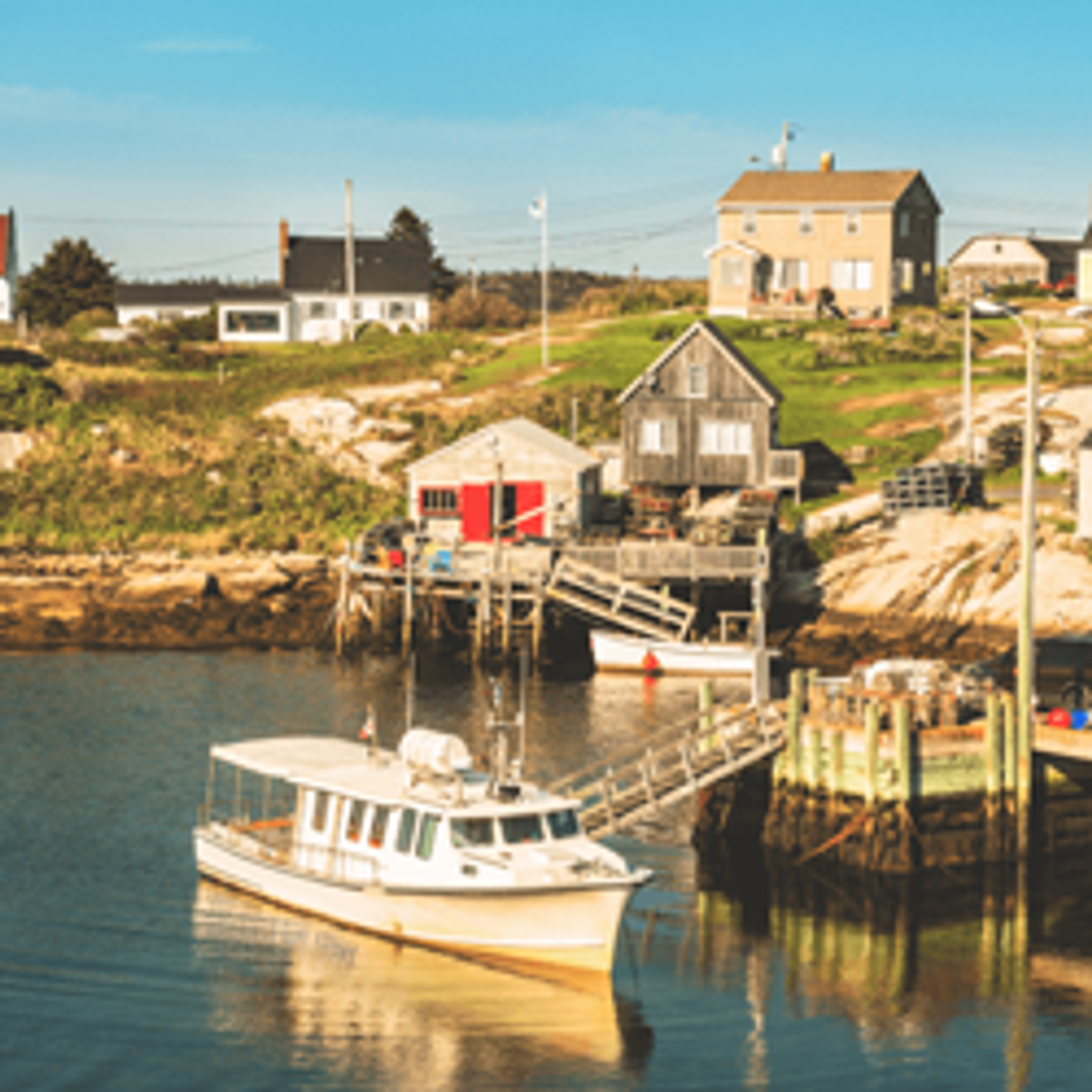 Boot auf dem Wasser vor der Küste mit Holzhäusern in Nova Scotia