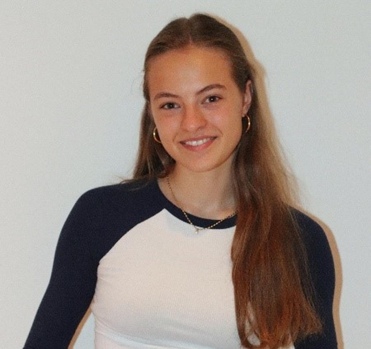 Mädchen mit langen braunen Haaren, silbernen Creolen und lächelnd