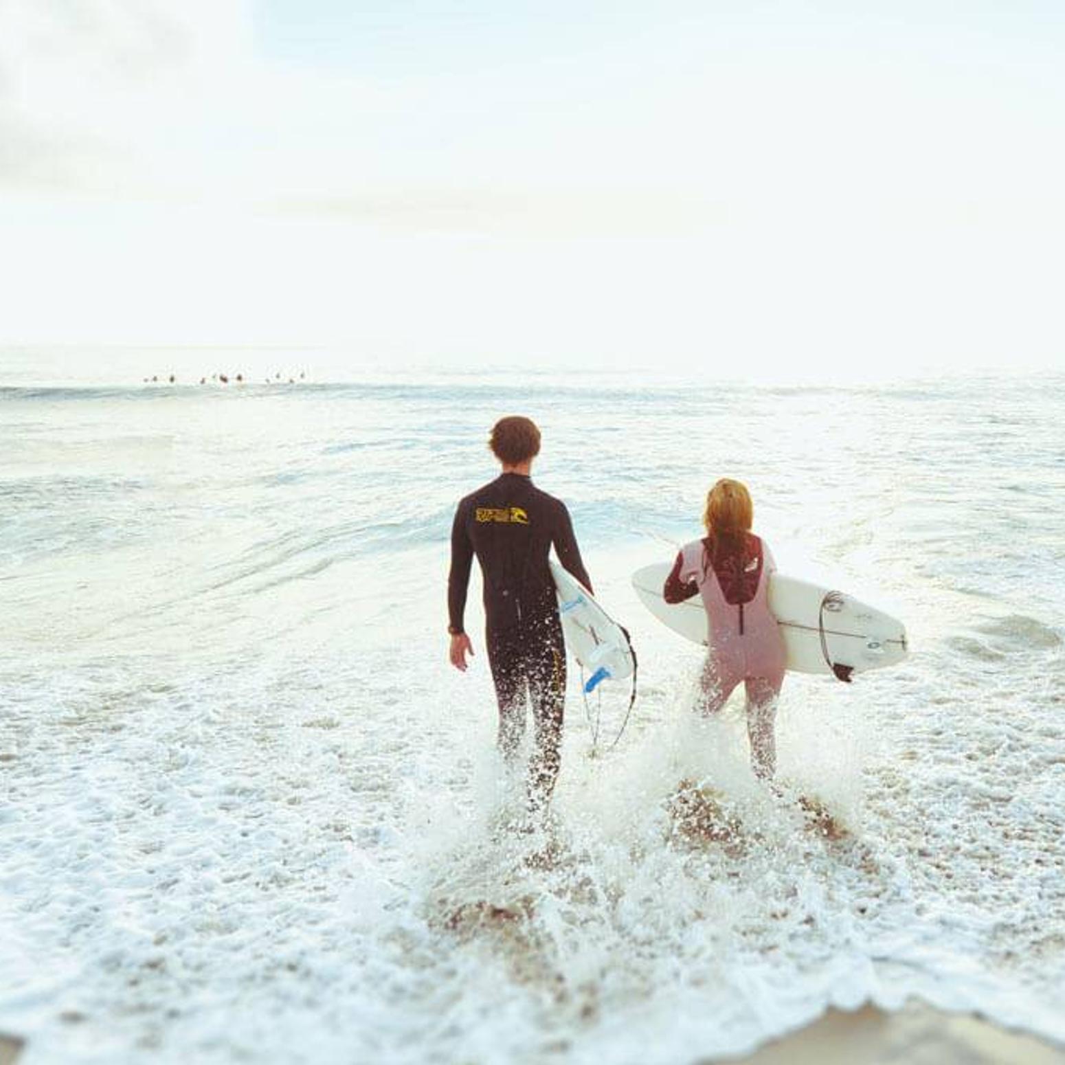 Bild von zwei Surfer die in das Meer laufen