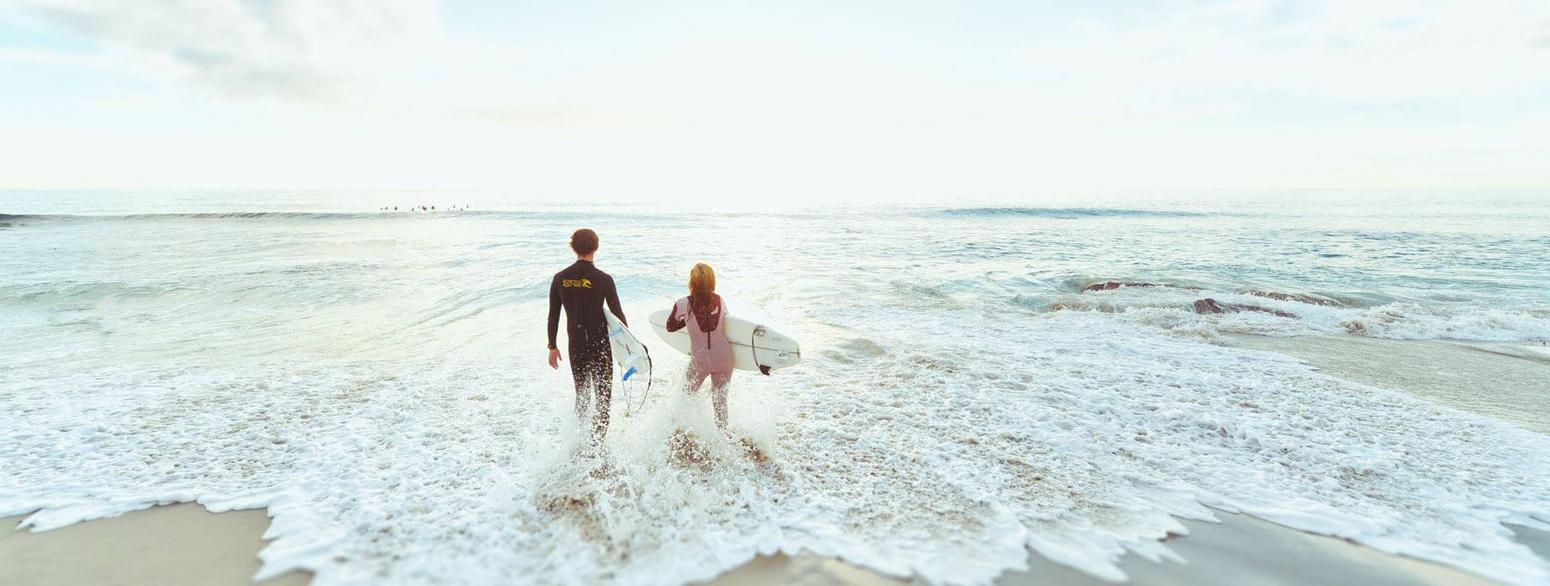 Bild von zwei Surfer die in das Meer laufen