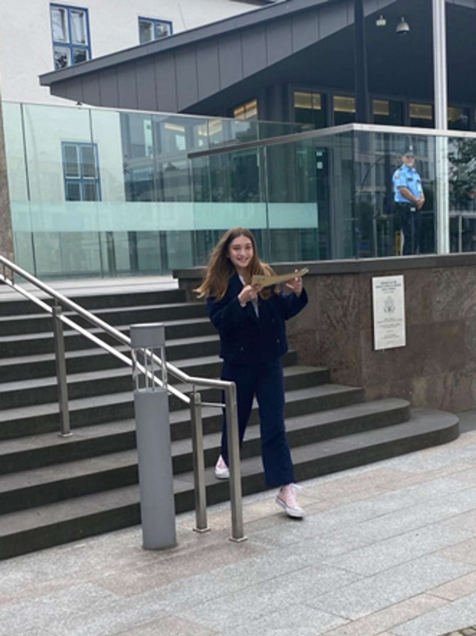 Teenager-Mädchen lächelt auf einer Treppe und hält eine Pappmappe