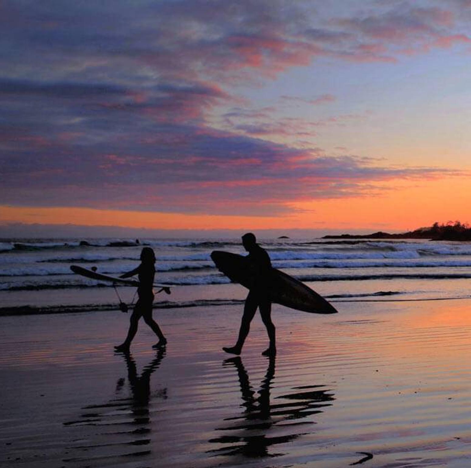 Zwei Surfer laufen bei Sonnenuntergang am Strand