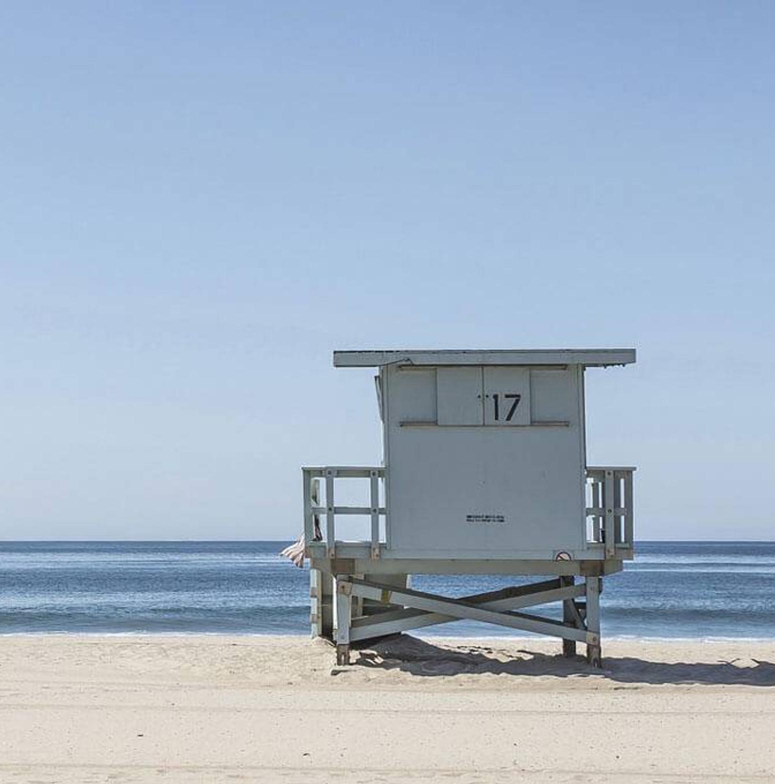 Eine Frau steht neben einer Strandhütte am Strand