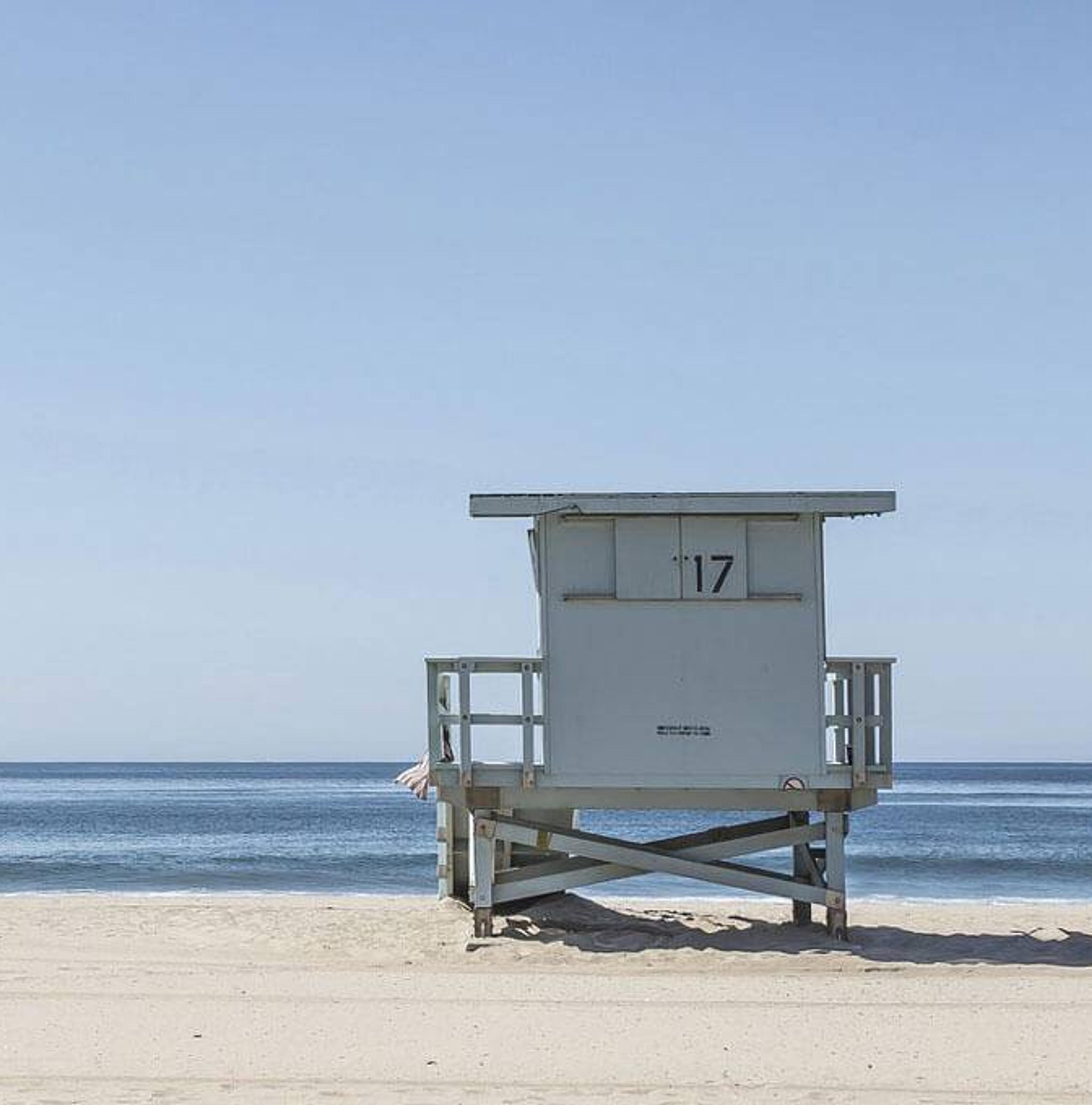 Eine Frau steht neben einer Strandhütte am Strand