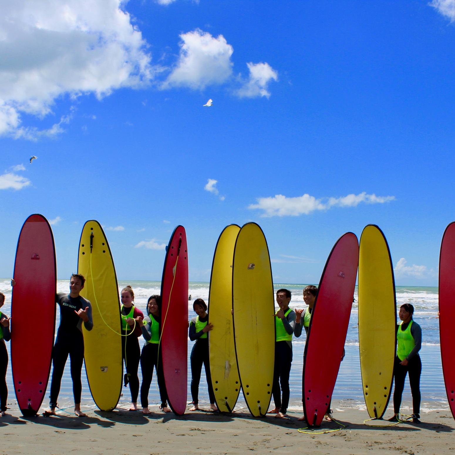 Ashburton College Christchurch Surfer:innen am Strand mit roten und gelben Surfbrettern