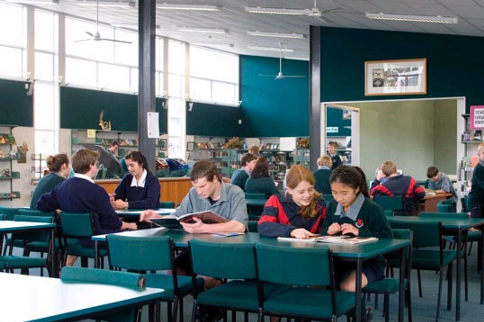 Schüler:innen lernen an Tischen im Schulgebäude