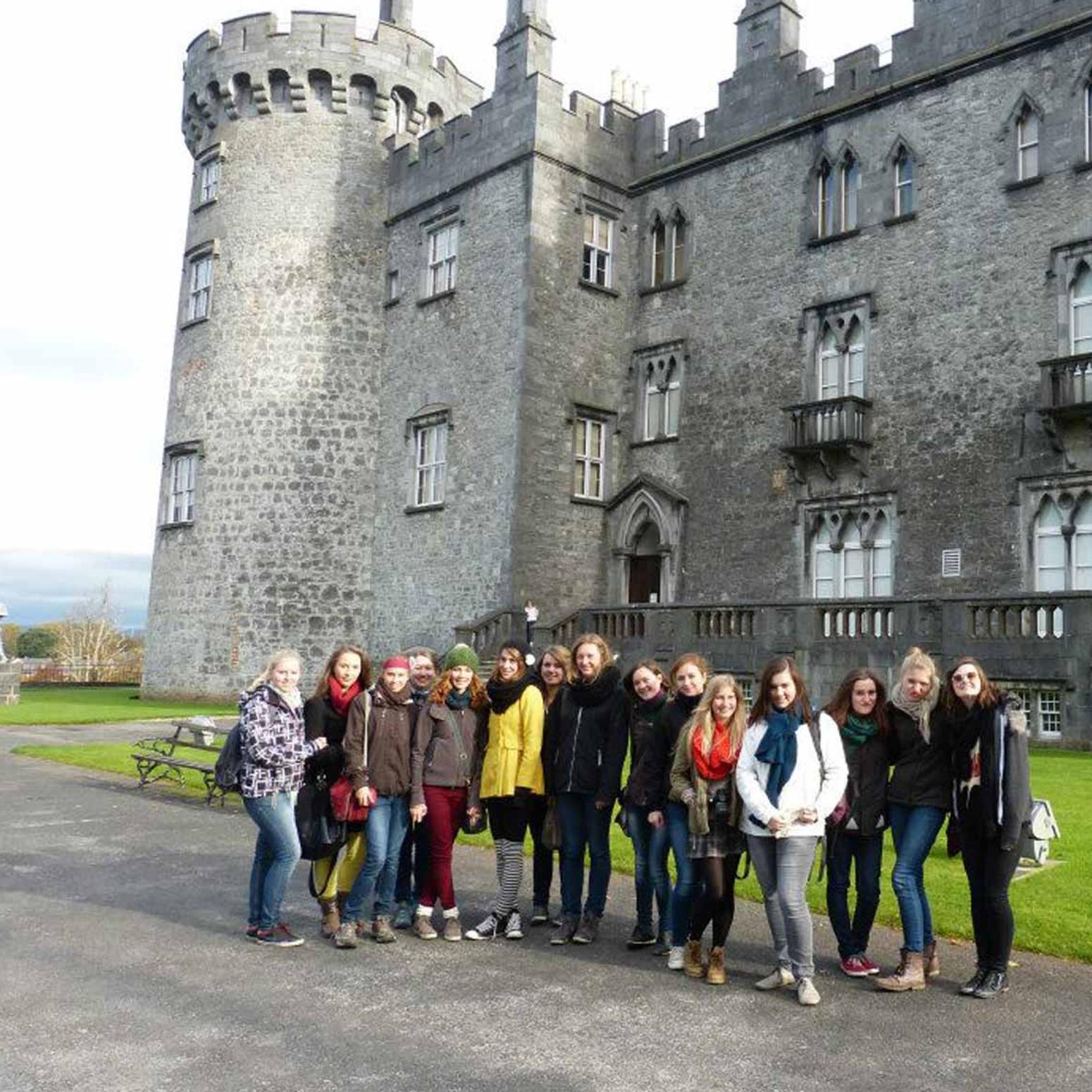 Gruppe von jungen Erwachsenen posieren vor einer Burg