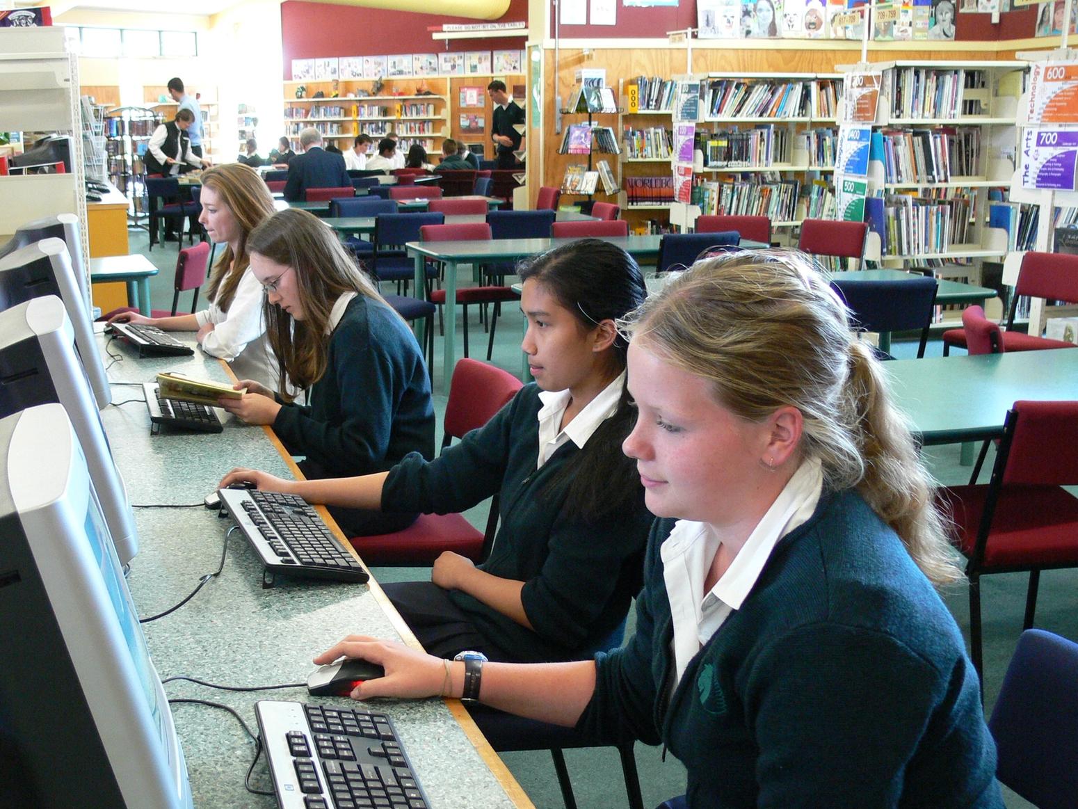 Schülerinnen vor Computer in der Schulbibliothek