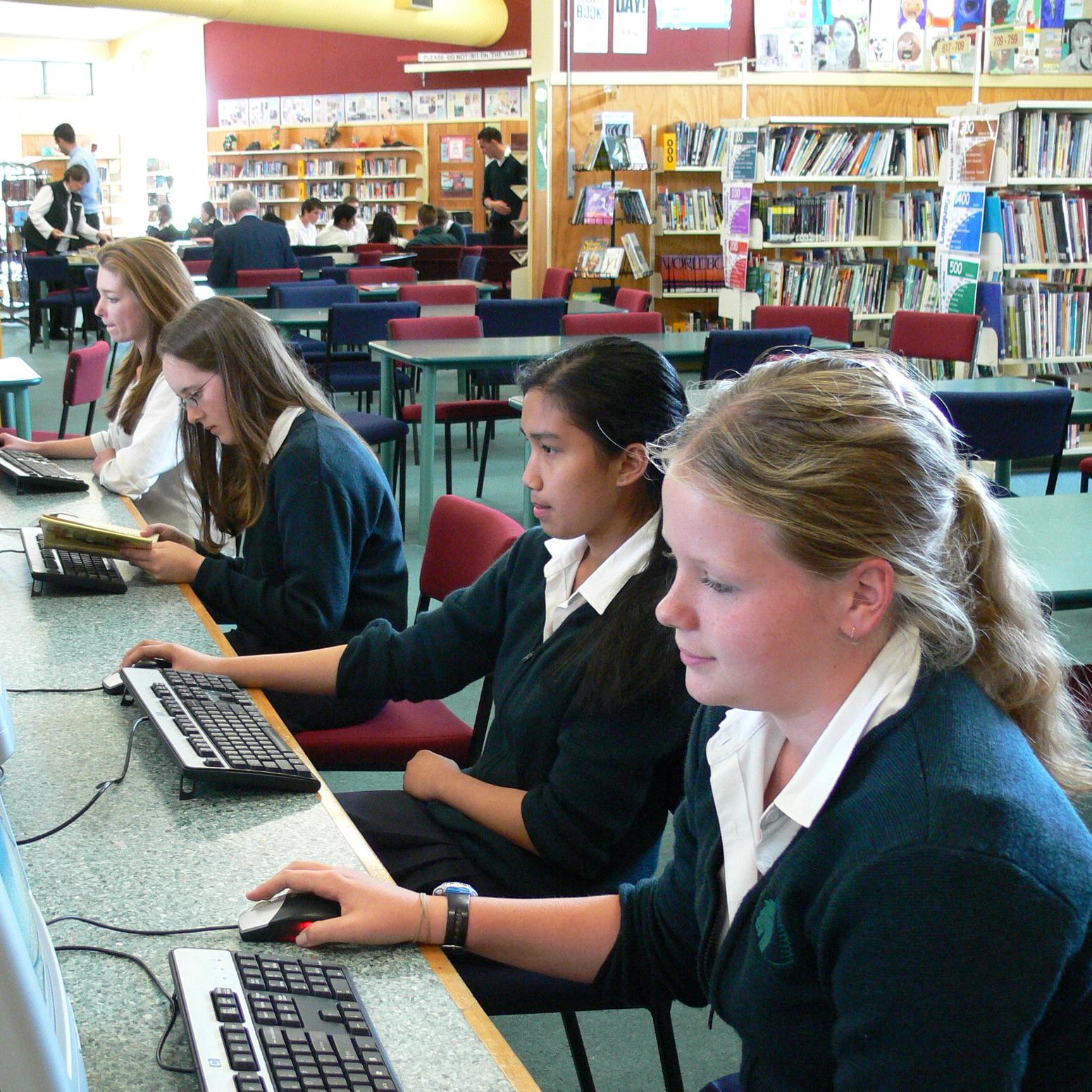Schülerinnen vor Computer in der Schulbibliothek