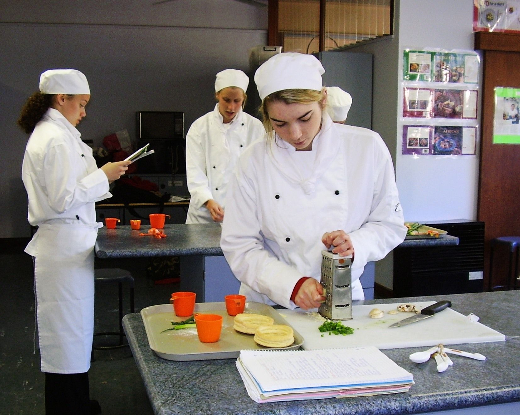 Schüler mit Koch-Uniformen, die in einer Küche gesunde Speisen zubereiten