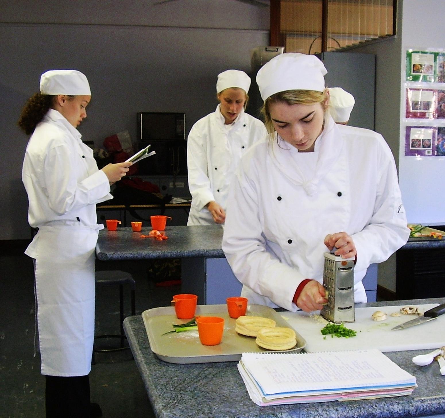 Schüler mit Koch-Uniformen, die in einer Küche gesunde Speisen zubereiten