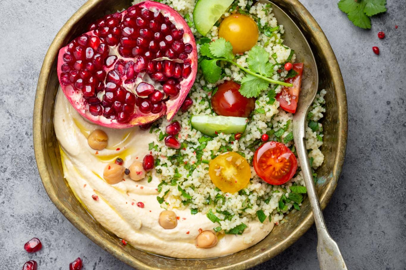 Salade de couscous avec légumes, houmous, grenade et coriandre fraîches