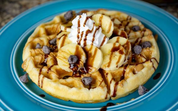 Gaufre avec bananes, beurre de cacahuète, filet de sirop de chocolat et pépites de chocolat