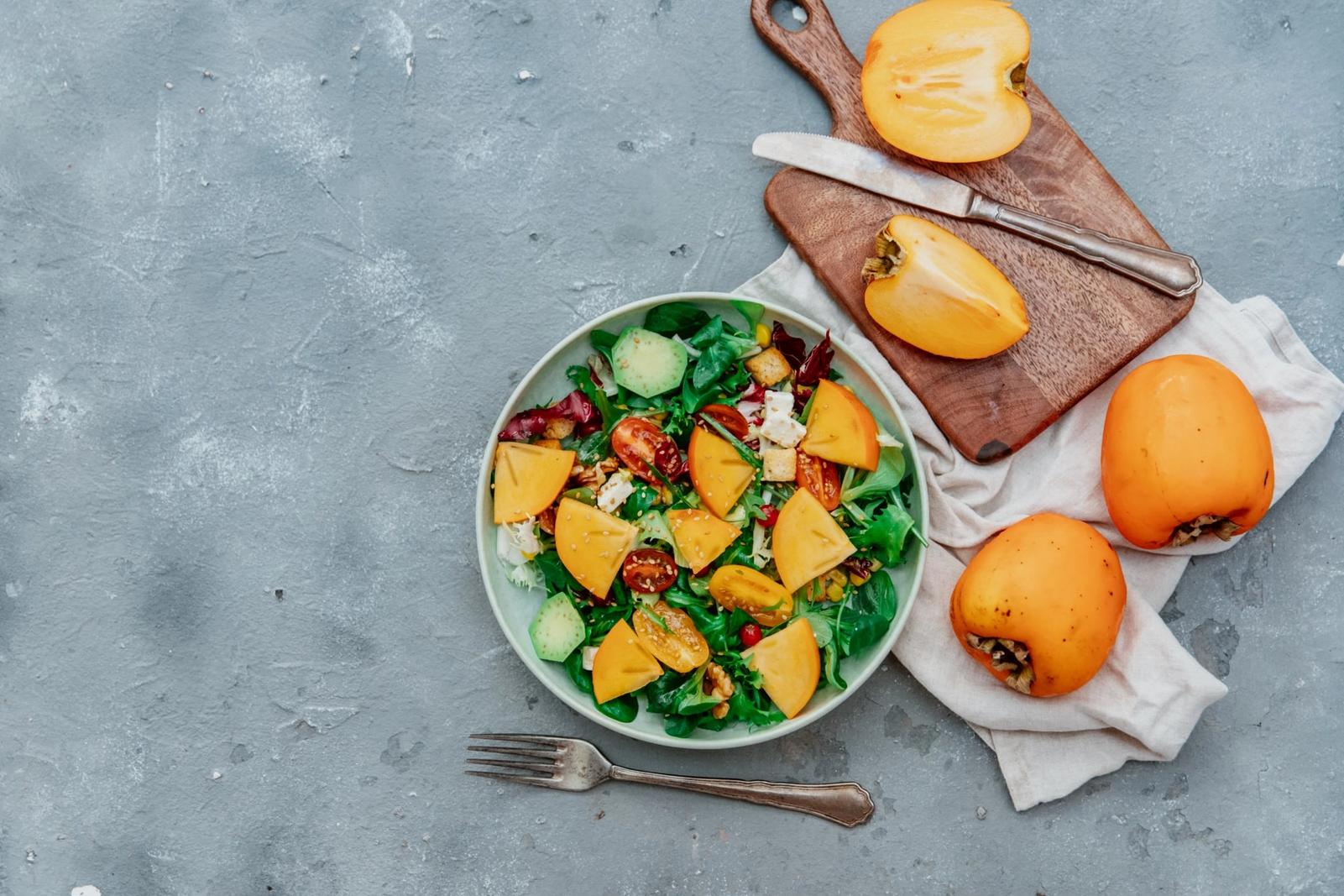 Salade de roquette, kakis, noix et légumes croquants