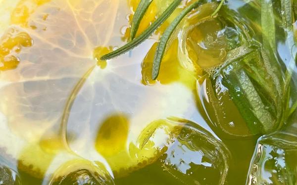 Thé vert détox froid avec tranches de citron, glaçons et feuilles de romarin