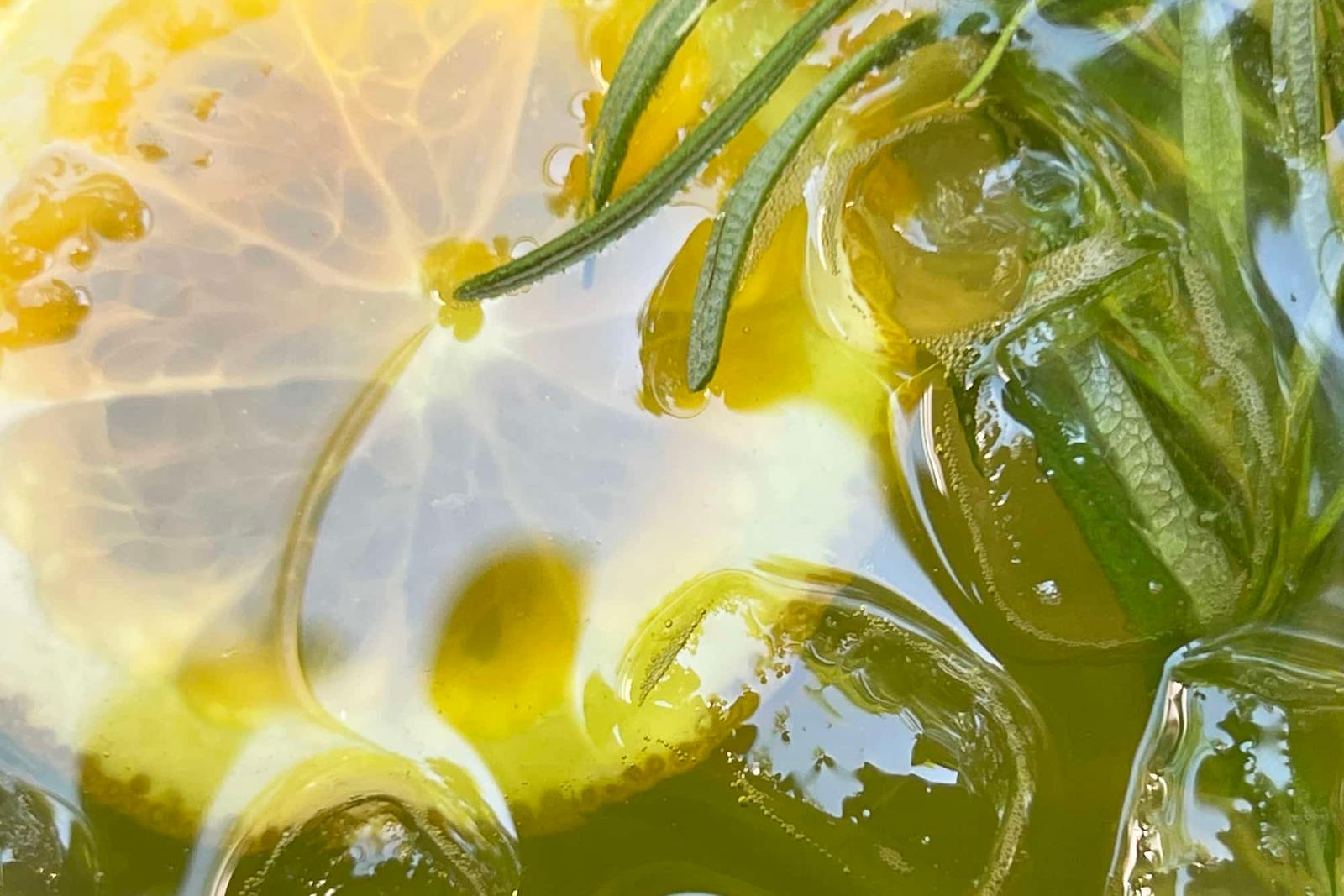 Thé vert détox froid avec tranches de citron, glaçons et feuilles de romarin