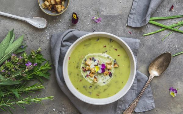 Soupe aux herbes crémeuse à l'oseille, fleurs comestibles et croutons