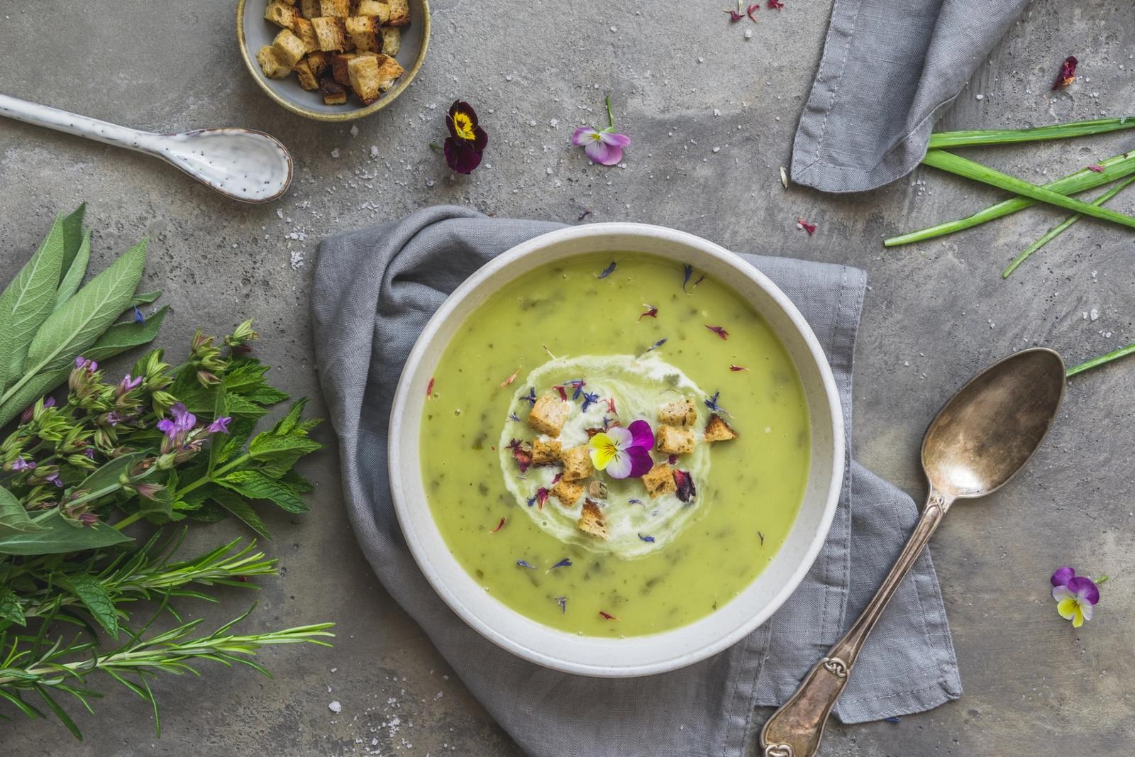 Soupe aux herbes crémeuse à l'oseille, fleurs comestibles et croutons