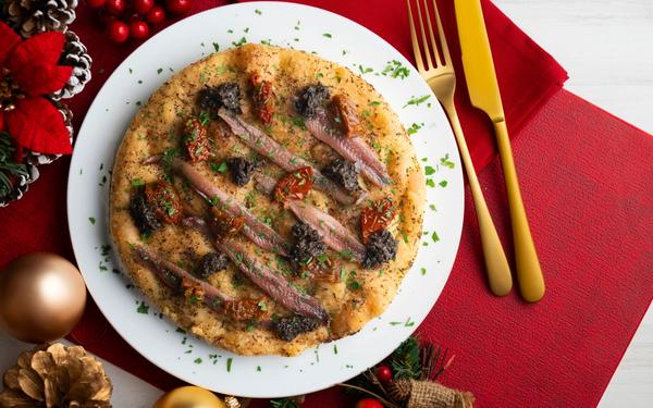 Focaccia italienne authentique aux anchois salés, tomates séchées et olives noires
