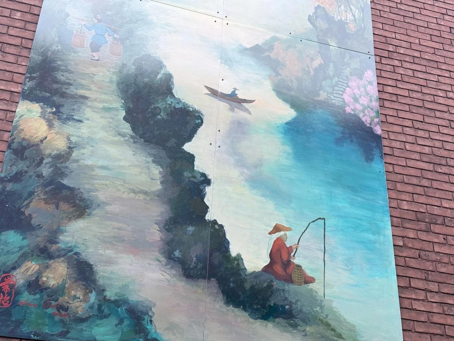 Peinture murale de Yi Chang, située au 637, rue Somerset Ouest, dans le quartier chinois d’Ottawa, représentant un paysage traditionnel chinois dans des tons de bleu profond, avec des traces de pinceau visibles, et un pêcheur tourné vers l’édifice