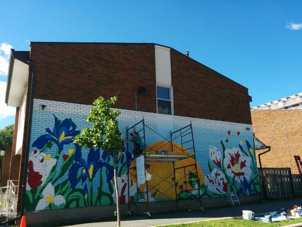 Vibrant Illunaata community mural by Maya Hum and OSA at Lowertown Community House. Celebrates Canadian diversity.