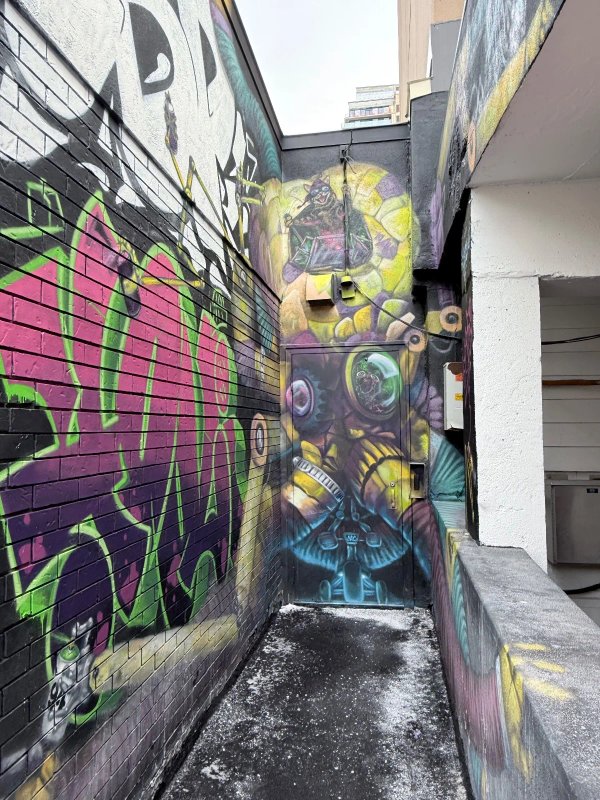 Artistic detail of a robot hand spray painting a wall, part of the Graffiti Octobot mural in Ottawa. This piece by local artist Martin Freundorfer highlights the evolution of public art in the Hintonburg community.