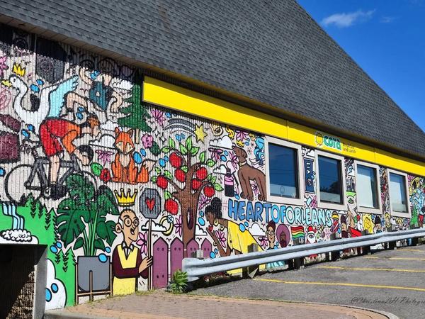 Colourful street art mural of cartoon figures and 'HEART TO ORLEANS' text on a building, St. Joseph Boulevard, Convent Glen South, Ottawa.