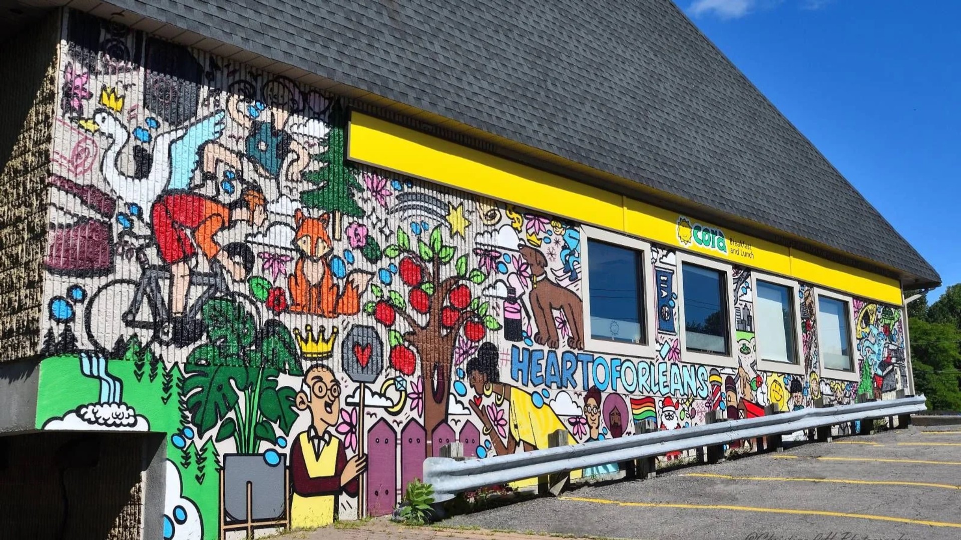 Colourful street art mural of cartoon figures and 'HEART TO ORLEANS' text on a building, St. Joseph Boulevard, Convent Glen South, Ottawa.