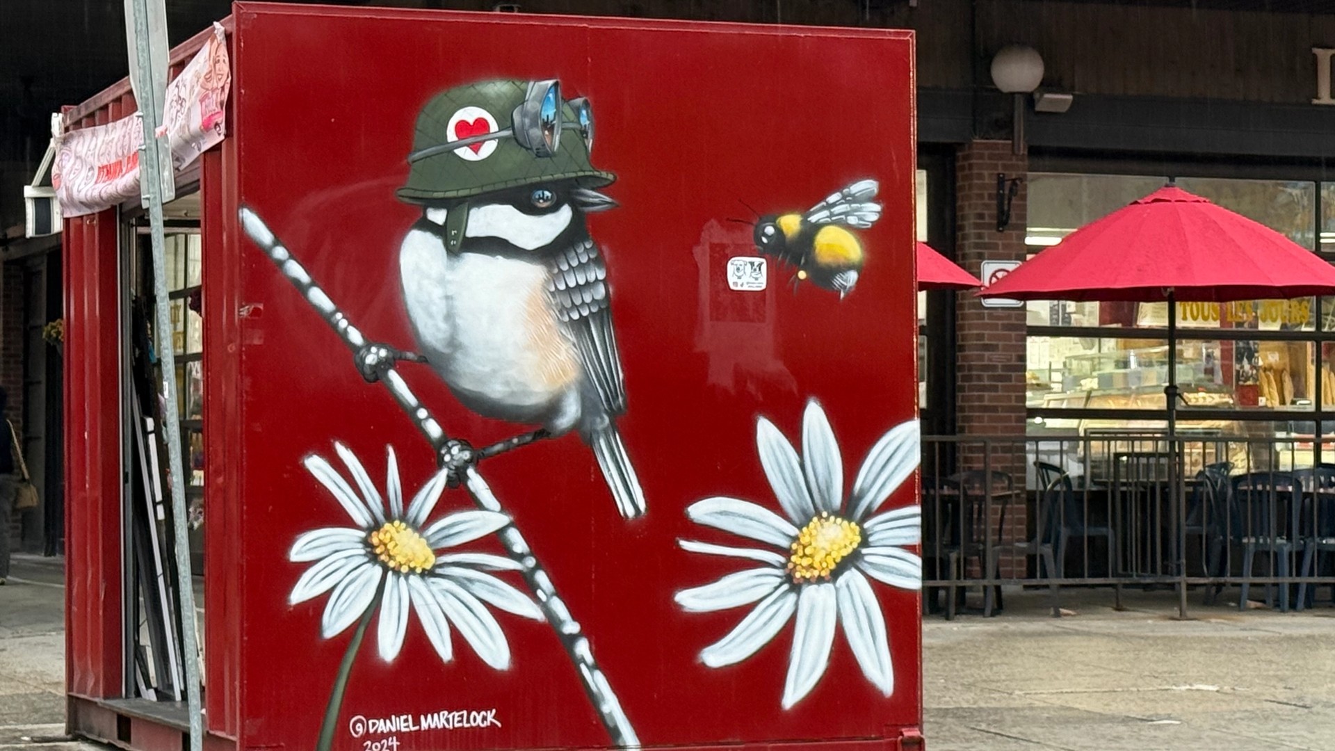 Urban bird mural by Ottawa artist Daniel Martelock featuring a chickadee in a flight helmet and a bumblebee. Located in Ottawa's historic Byward Market, this street art is part of the OTTAWALLS living archive of National Capital Region murals.
